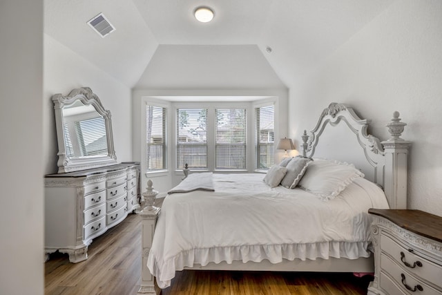 bedroom with visible vents, vaulted ceiling, and wood finished floors