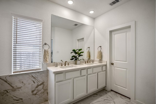 bathroom featuring marble finish floor, visible vents, a sink, and double vanity