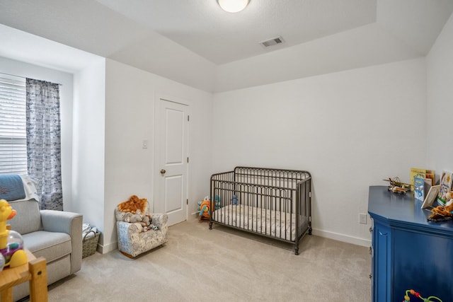 bedroom featuring light carpet, a nursery area, baseboards, and visible vents