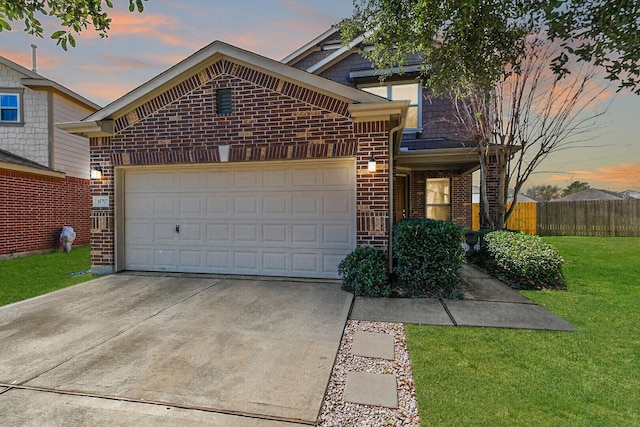 view of front of home featuring driveway, a lawn, an attached garage, fence, and brick siding