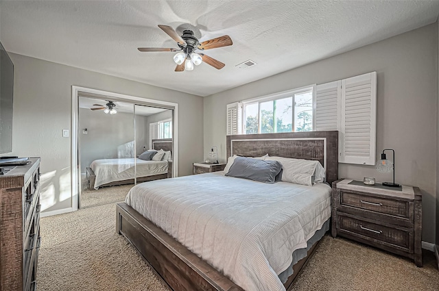 bedroom featuring visible vents, ceiling fan, carpet, a textured ceiling, and a closet