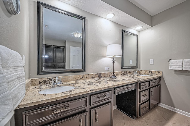 full bathroom with double vanity, a sink, baseboards, and tile patterned floors