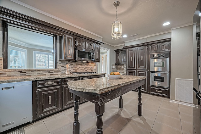 kitchen with stainless steel appliances, ornamental molding, light tile patterned flooring, and pendant lighting