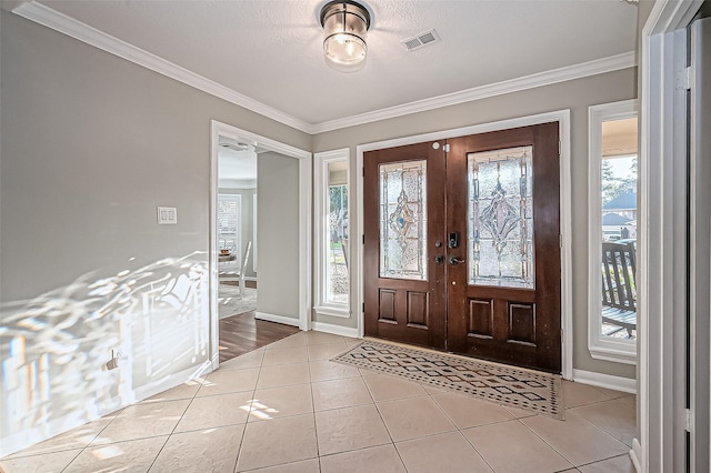 foyer with ornamental molding, visible vents, baseboards, and light tile patterned flooring