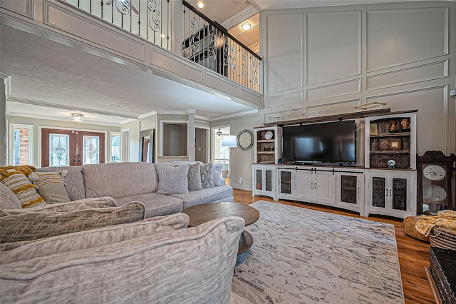 living area with ornamental molding, french doors, a high ceiling, and wood finished floors