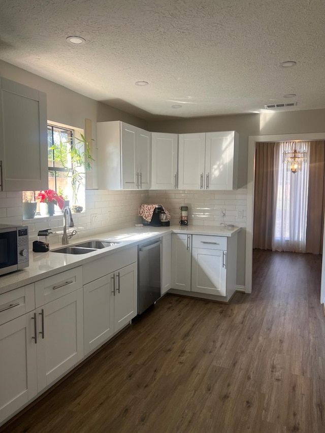 kitchen featuring stainless steel appliances, dark wood-style flooring, a sink, white cabinets, and light countertops