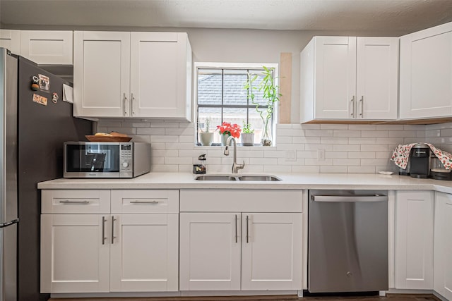kitchen with light countertops, white cabinets, appliances with stainless steel finishes, and a sink