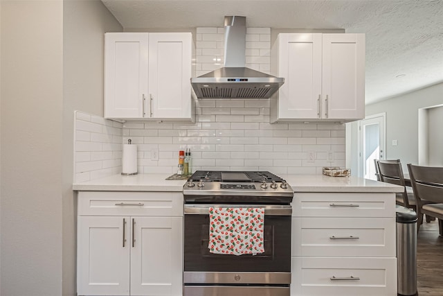 kitchen with decorative backsplash, light countertops, white cabinetry, wall chimney exhaust hood, and stainless steel gas stove