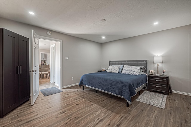 bedroom featuring recessed lighting, a textured ceiling, baseboards, and wood finished floors