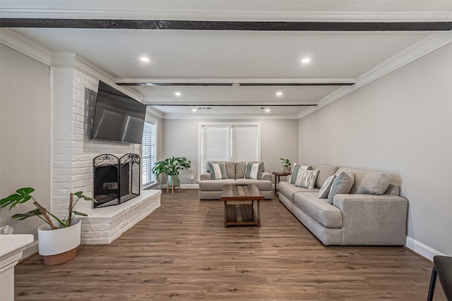 living room featuring beamed ceiling, a brick fireplace, baseboards, and wood finished floors