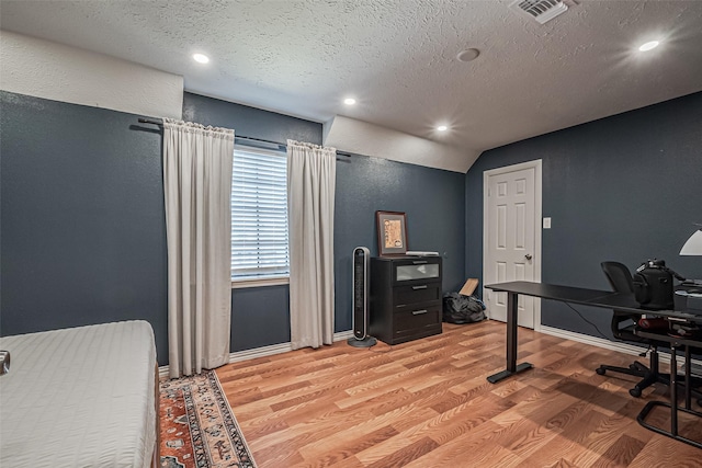 office area featuring visible vents, lofted ceiling, a textured ceiling, and light wood-style flooring