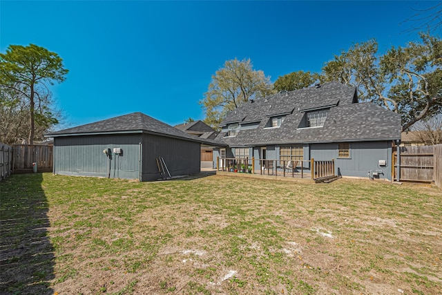 rear view of property featuring an outbuilding, a fenced backyard, a lawn, and roof with shingles