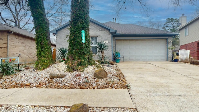 ranch-style home with driveway, an attached garage, roof with shingles, and brick siding