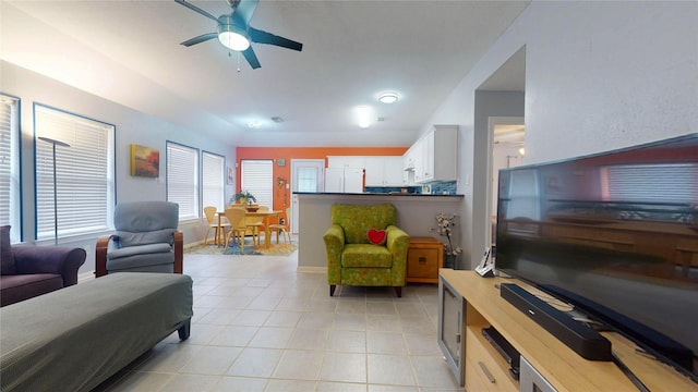 living area featuring light tile patterned floors, ceiling fan, and baseboards