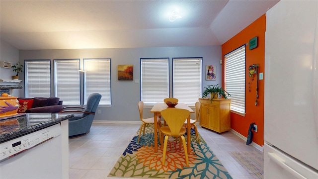 dining area with lofted ceiling, light tile patterned floors, a healthy amount of sunlight, and baseboards