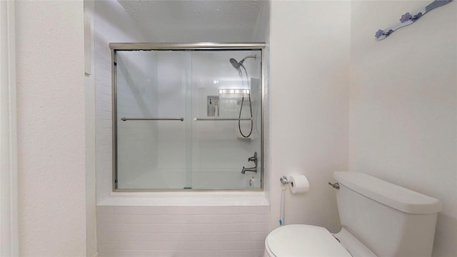 bathroom featuring toilet and bath / shower combo with glass door