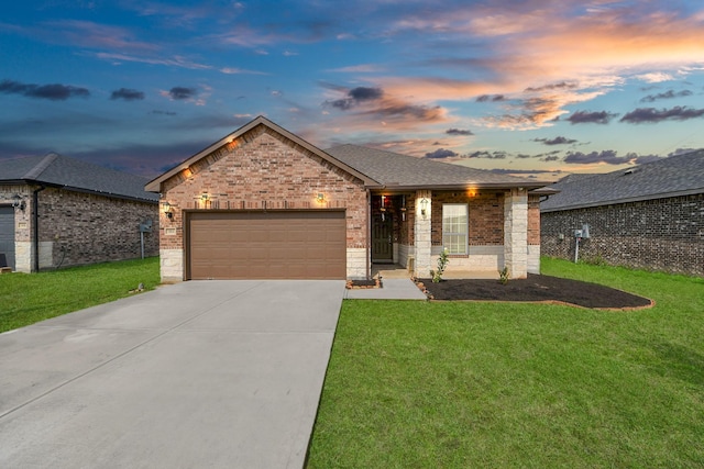 ranch-style home with a lawn, driveway, roof with shingles, an attached garage, and brick siding