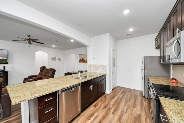 kitchen featuring visible vents, a peninsula, arched walkways, stainless steel appliances, and a sink