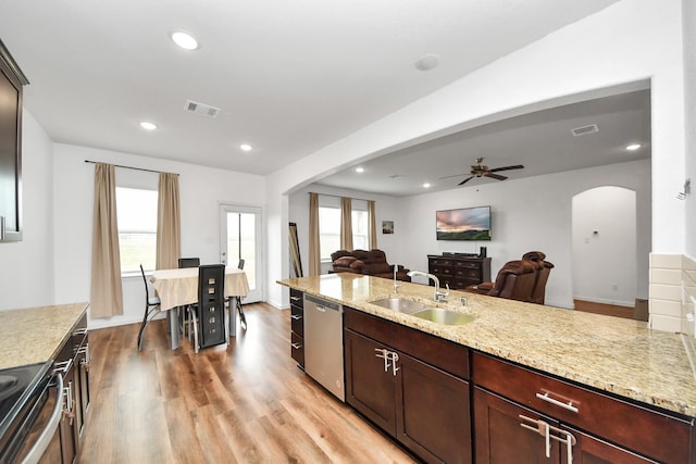 kitchen featuring arched walkways, stainless steel appliances, light wood-type flooring, and a sink