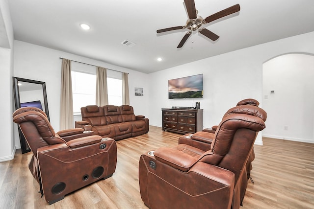 living room with baseboards, visible vents, arched walkways, and light wood-type flooring