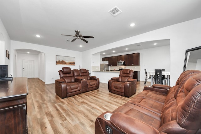 living room with light wood-style flooring, recessed lighting, arched walkways, and visible vents