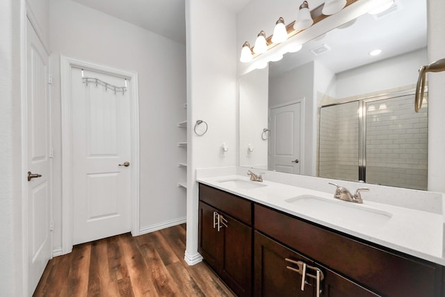 bathroom featuring visible vents, a shower stall, wood finished floors, and a sink