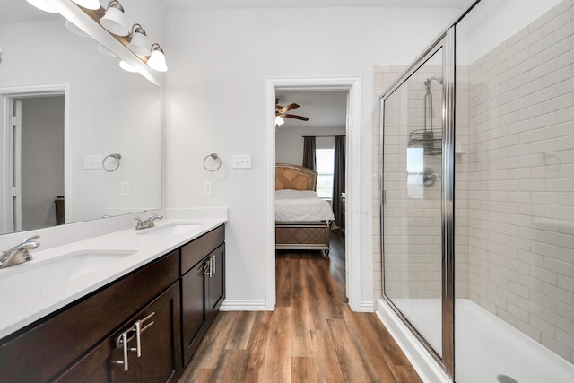 ensuite bathroom with a stall shower, wood finished floors, ensuite bathroom, and a sink