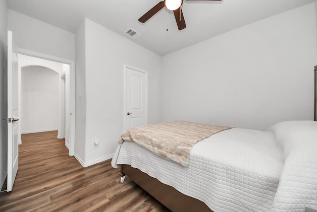 bedroom with visible vents, a ceiling fan, wood finished floors, arched walkways, and baseboards