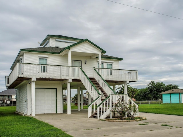 coastal home featuring a carport, a front yard, concrete driveway, and a shingled roof