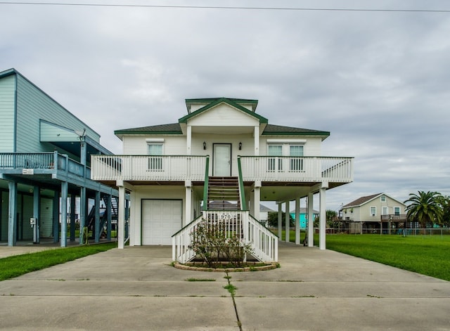 beach home with a shingled roof, concrete driveway, stairway, a garage, and a carport