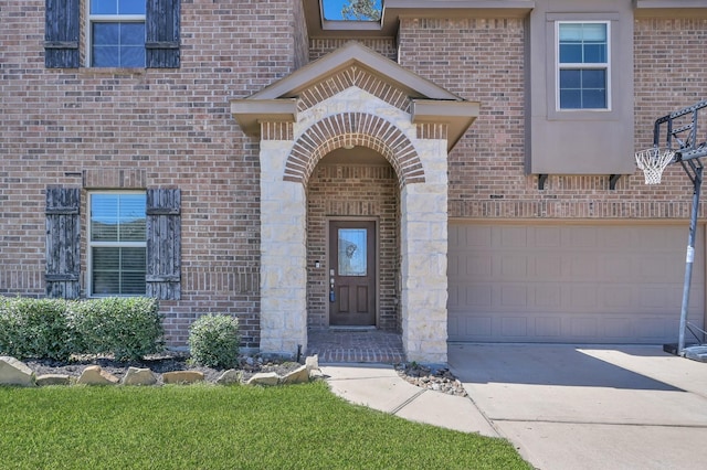 view of exterior entry featuring stone siding, a garage, brick siding, and driveway