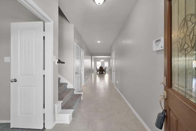 hall featuring light tile patterned floors, stairway, and baseboards