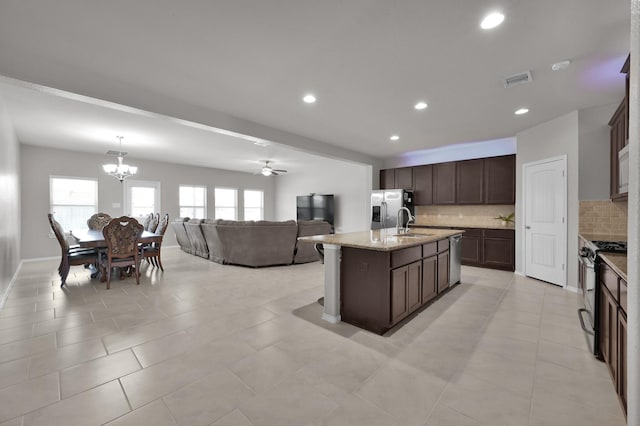 kitchen featuring a sink, dark brown cabinets, open floor plan, and gas range oven