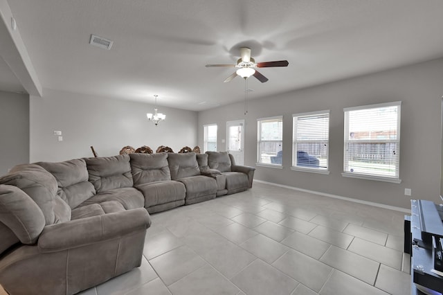 living area with light tile patterned flooring, visible vents, ceiling fan with notable chandelier, and baseboards