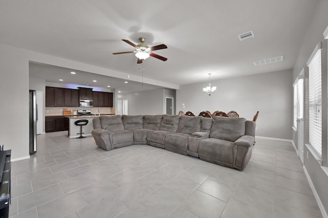 living room featuring light tile patterned floors, ceiling fan with notable chandelier, visible vents, and baseboards