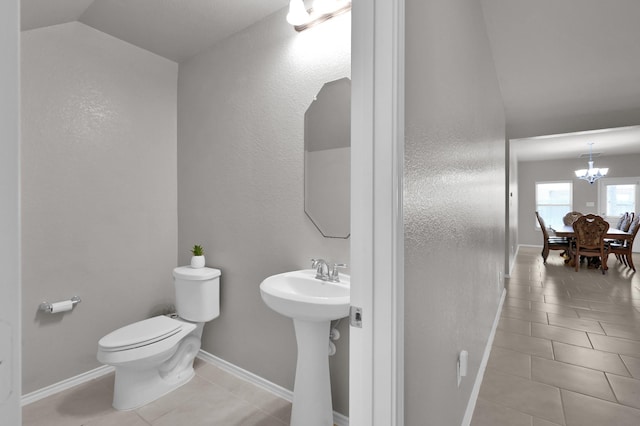 bathroom featuring tile patterned flooring, toilet, baseboards, and vaulted ceiling