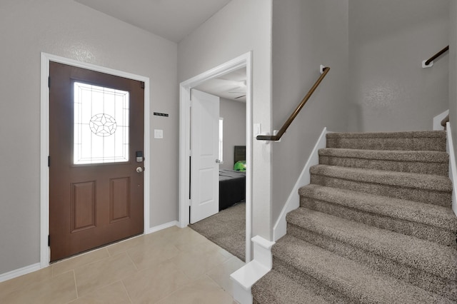 entryway featuring baseboards, light tile patterned flooring, and stairs