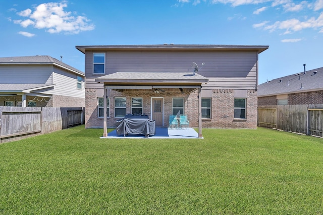 rear view of house featuring brick siding, a yard, and a fenced backyard