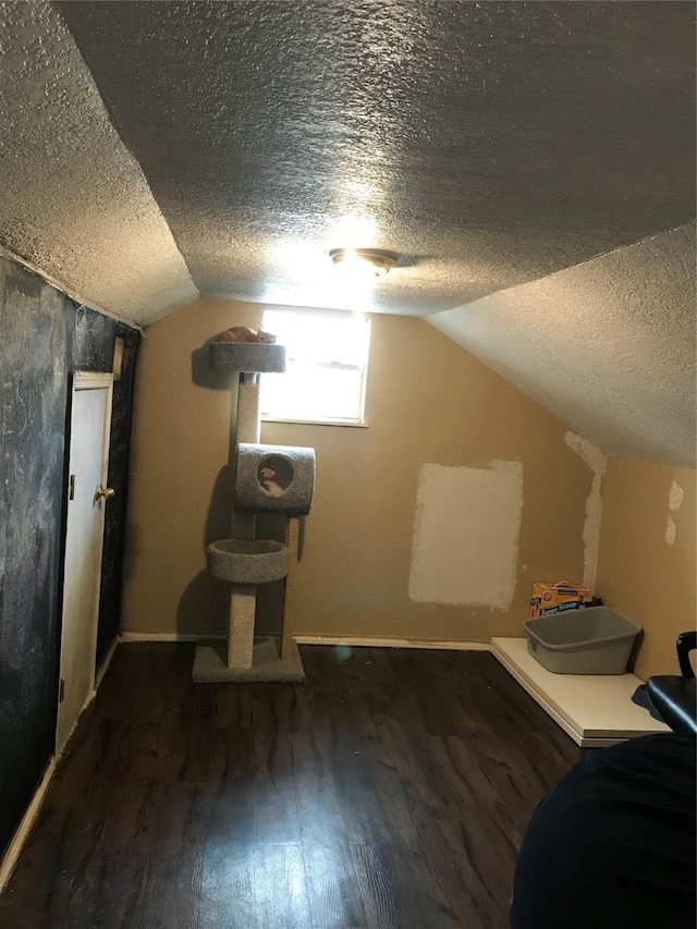 bonus room with a textured ceiling, vaulted ceiling, and wood finished floors