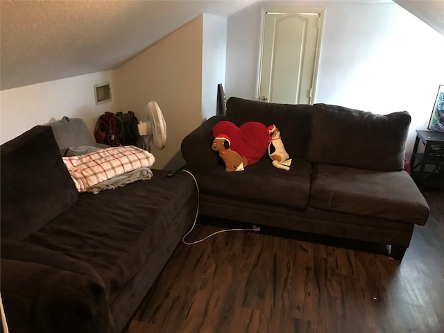 living area with visible vents, vaulted ceiling, a textured ceiling, and wood finished floors