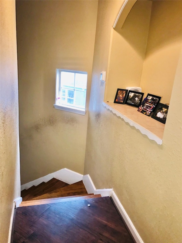 stairway featuring baseboards and wood finished floors