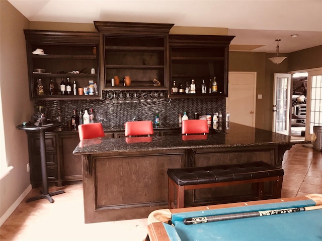 bar with baseboards, light tile patterned flooring, backsplash, and bar