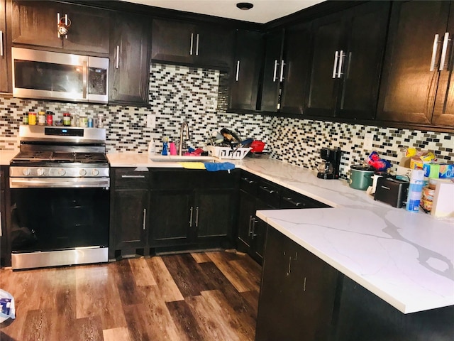 kitchen with stainless steel appliances, dark wood-type flooring, and dark cabinetry