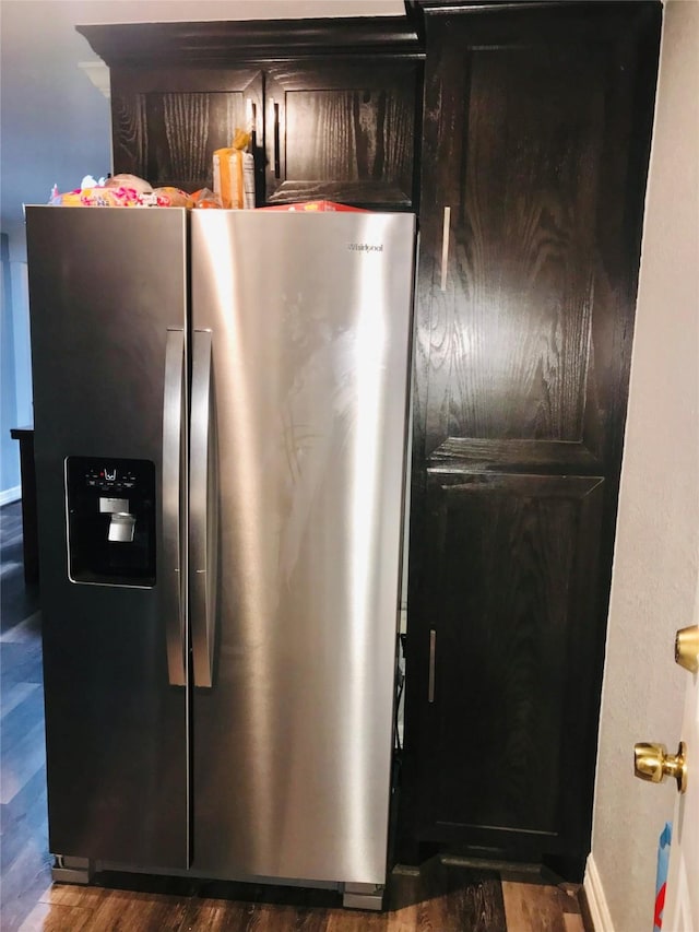 interior space with dark wood-type flooring, stainless steel fridge, and baseboards