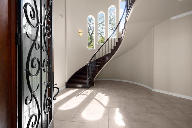 tiled foyer with stairs, visible vents, and baseboards