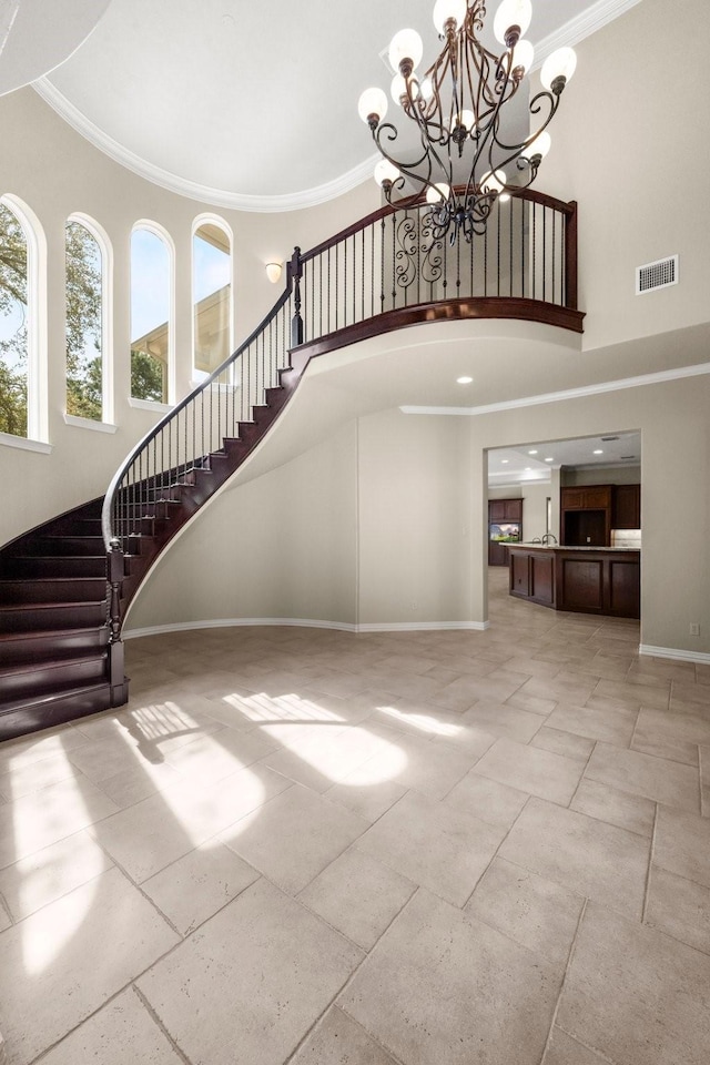 interior space featuring a high ceiling, baseboards, visible vents, and ornamental molding