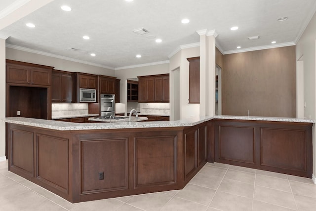 kitchen with stainless steel microwave, light stone counters, tasteful backsplash, and light tile patterned floors