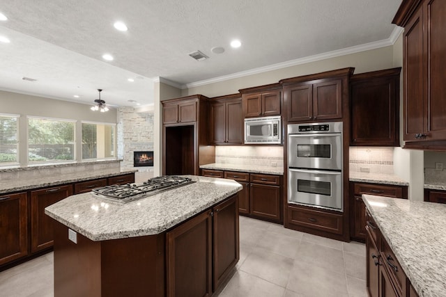 kitchen with tasteful backsplash, visible vents, stainless steel appliances, and ornamental molding