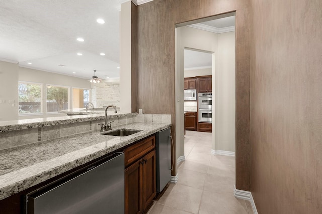 kitchen featuring ornamental molding, a sink, light stone counters, appliances with stainless steel finishes, and light tile patterned floors