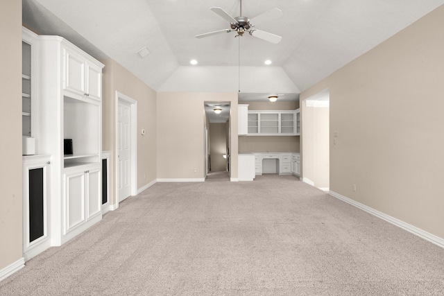 unfurnished living room featuring baseboards, lofted ceiling, light colored carpet, and built in desk